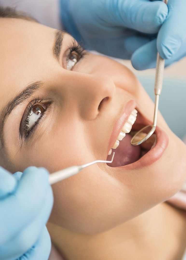 Lächelnde Patientin bei zahnärztlicher Untersuchung, Nahaufnahme mit Instrumenten